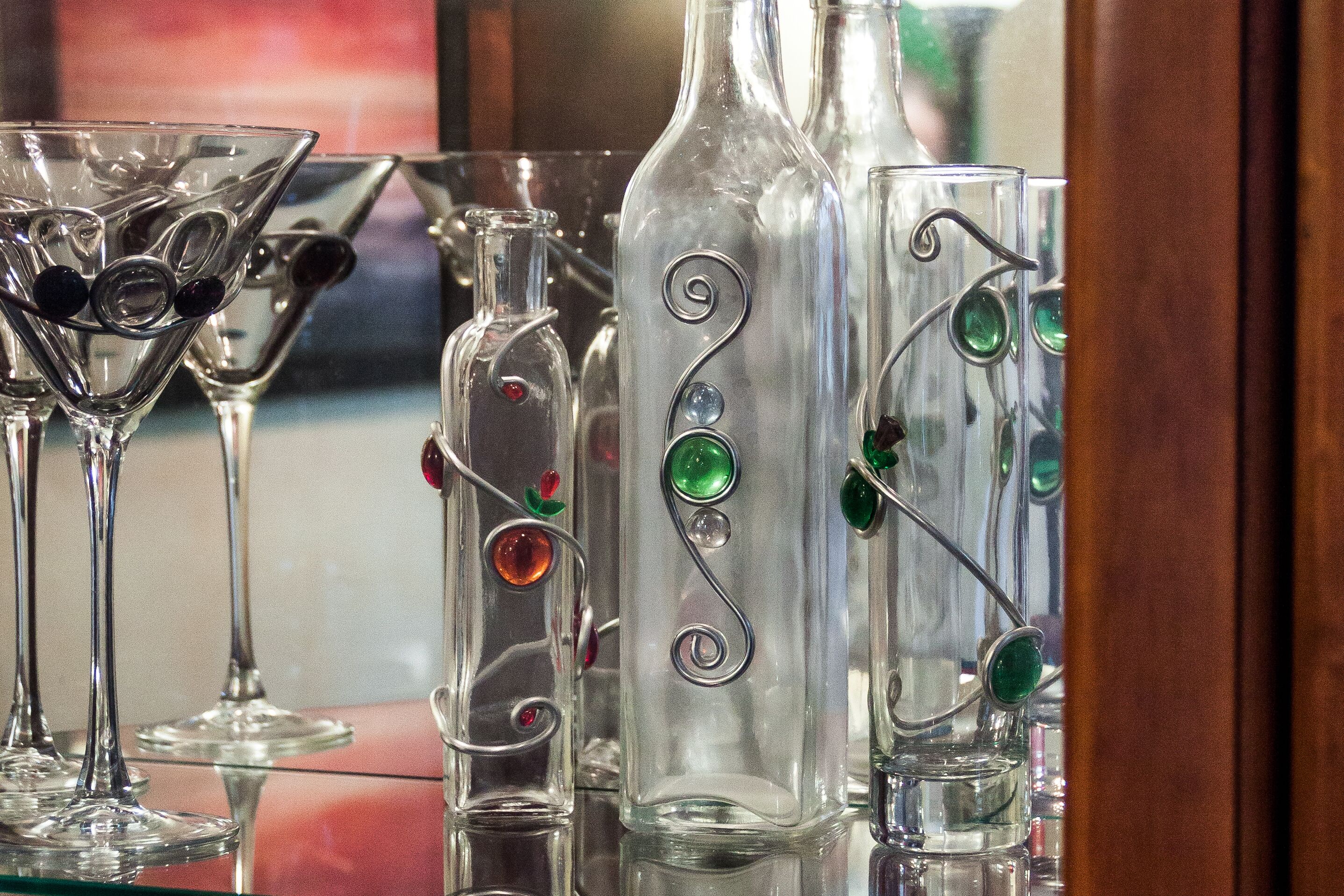 A collection of clear glass bottles with decorative metal spirals and gemstones.