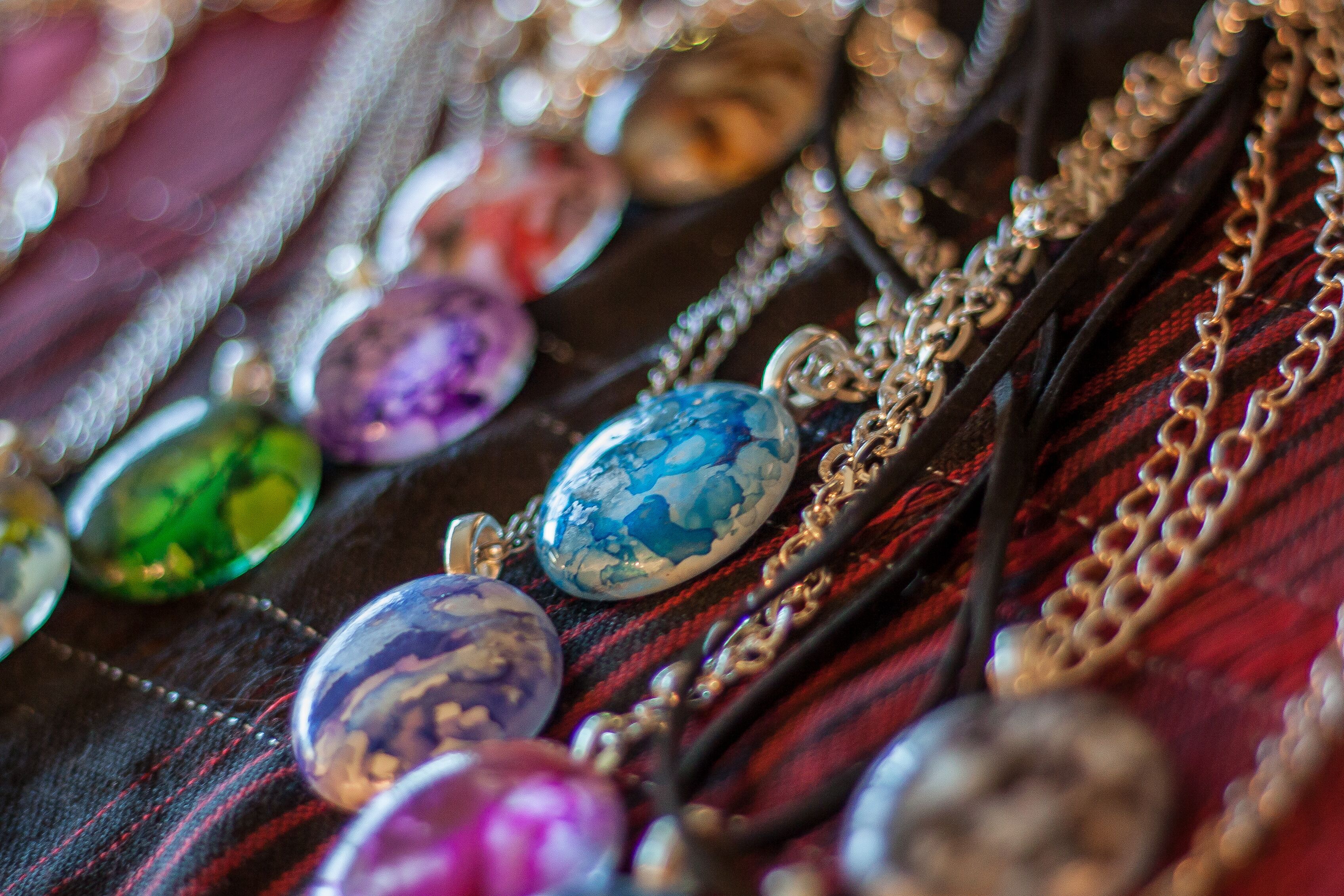 A collection of colorful gemstones and jewelry on a fabric background.