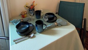 A dining table set with plates, bowls, and cutlery, a vase with flowers, and a framed painting above.