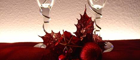 Two glasses with red liquid, decorated with red ornaments and a bow, on a dark surface.