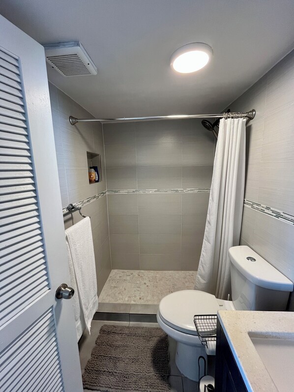 A bathroom with a shower, toilet, and a towel rack.