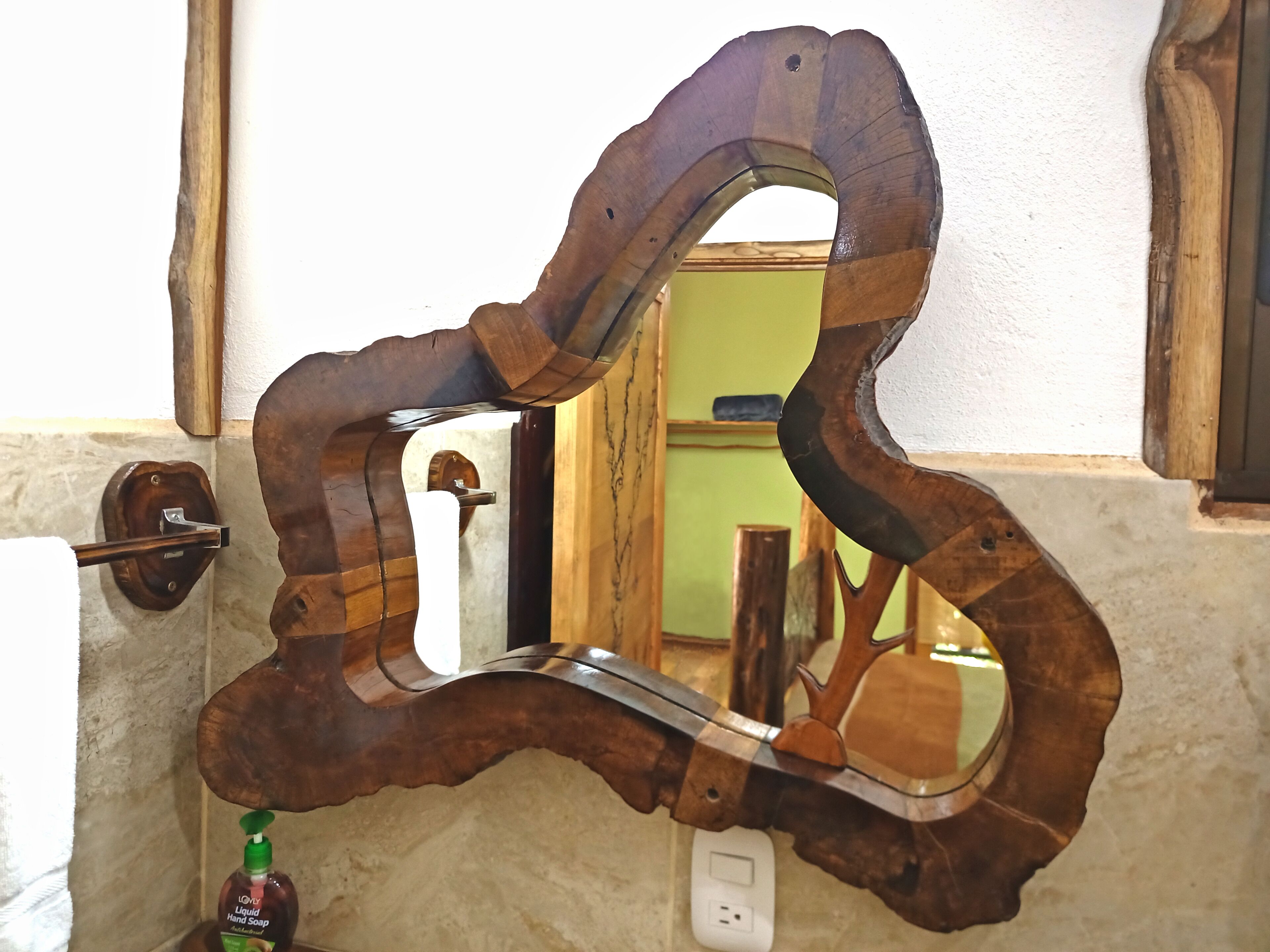 Ein Badezimmer mit einem hölzernen Spiegel mit einem einzigartigen, gewölbten Design.