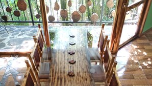 A wooden dining table with a glass top and six chairs. - Canopy Wonders House: A Place Among Tree Tops! (Monteverde)