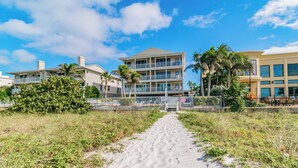 A beachfront hotel with a sandy pathway leading to the entrance, surrounded by palm trees and other greenery. - 2 Bedroom In Indian Rocks Beach, FL - Gulf Side Complex w/ Direct Beach Access (Indian Rocks Beach)