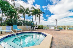A pool area with a hot tub, lounge chairs, and a sign detailing spa rules.