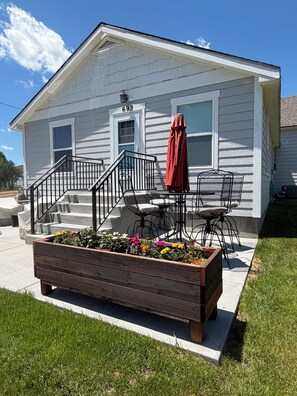 A residential house with a porch, outdoor seating, and a flower bed.