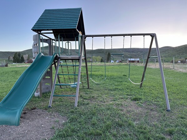 Un parque infantil con un tobogán, columpios y una estructura para escalar.