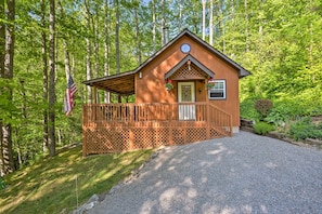 A wooden cabin with a covered porch, a front door, and a small window.