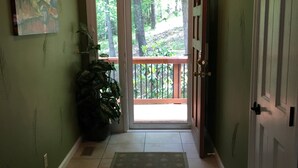 Un passadís amb una paret verda, una porta, una finestra i una planta en test.