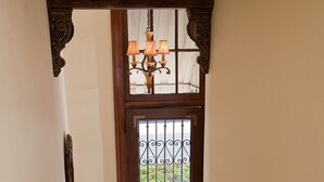 Un escalier en bois, doté d’une rampe métallique, mène à une porte surmontée d’un portail en fer forgé.