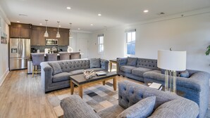 A spacious living room with a grey sofa set, a coffee table, and a lamp. - Walk to the Waterfront: Spacious Condo in the Heart of Newport (Newport)