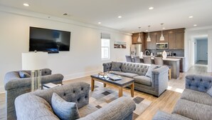 A modern living room with a large flat-screen TV, grey upholstered sofas, and a coffee table. - Walk to the Waterfront: Spacious Condo in the Heart of Newport (Newport)