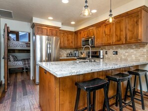 A kitchen with wooden cabinets, a stainless steel refrigerator, a microwave, and a granite countertop. - Ski the greatest snow on earth! (Park City)