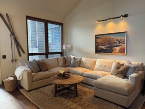 A living room with a sectional sofa, a wooden coffee table, and a painting on the wall. - Ski the greatest snow on earth! (Park City)