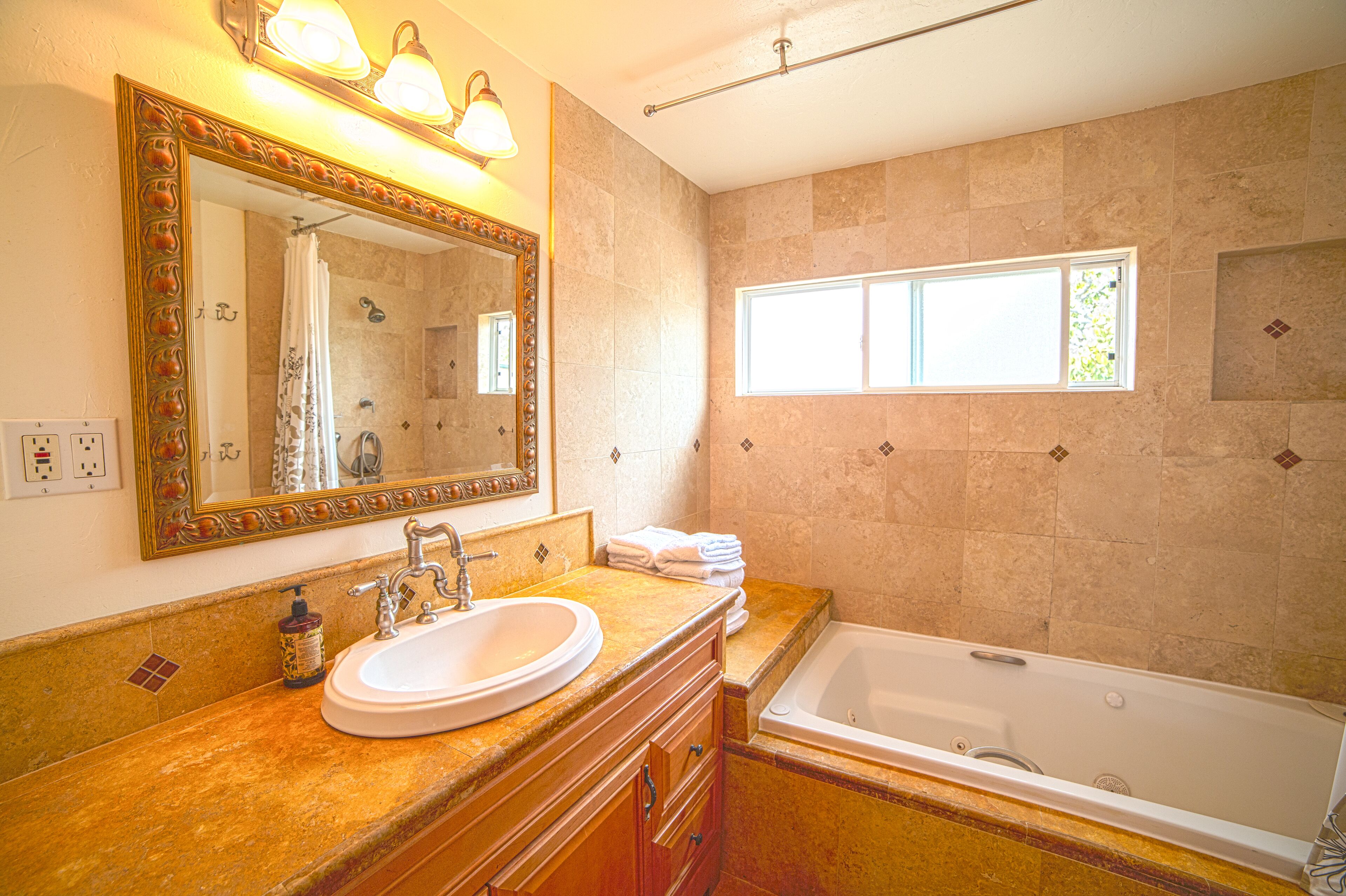 A bathroom with a sink, mirror, and bathtub.