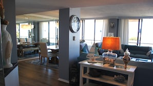 A spacious living room with a large window, a dining area, and a cozy seating area. -  Luxury 2400 Sq Ft Condo w/ Epic Views, Private Beach Access, Large Pool (Siesta Key)