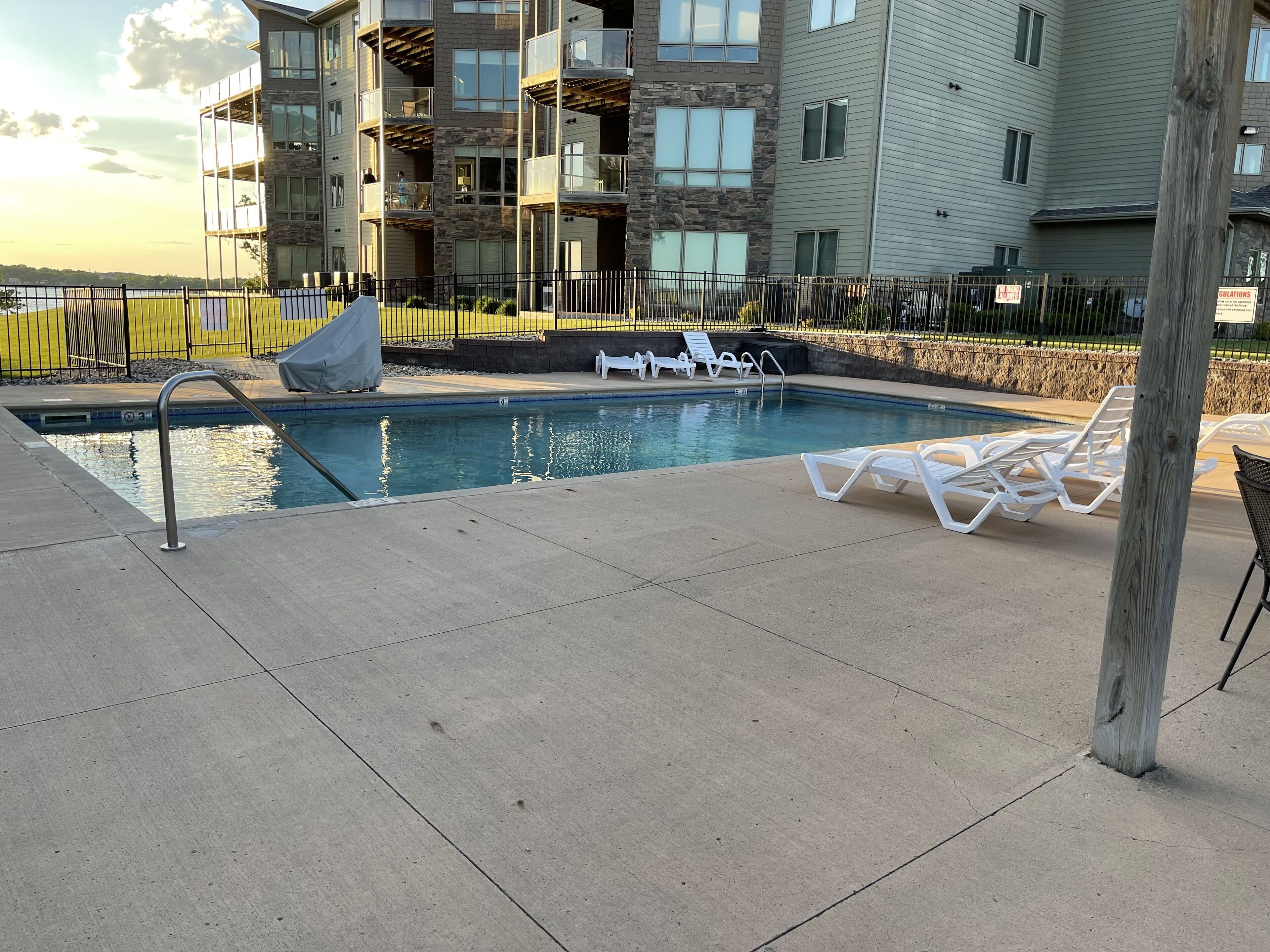 Une piscine avec des chaises longues et, en arrière-plan, un bâtiment à la façade en pierre.