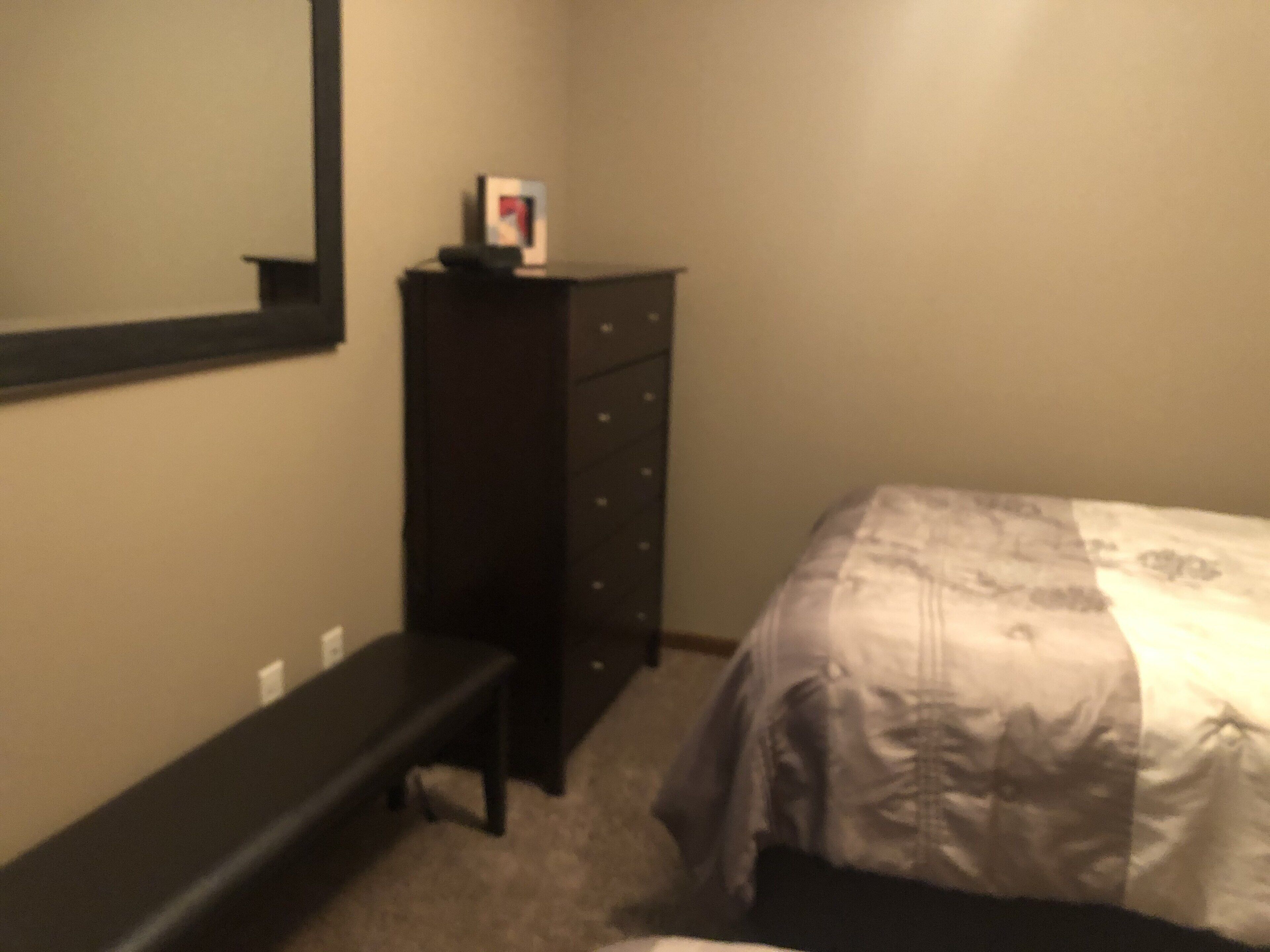 A bedroom with a bed, a dresser, and a bench.