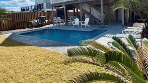 Ein zweistöckiges Haus mit Pool, Sitzgelegenheit im Freien und einer überdachten Terrasse.