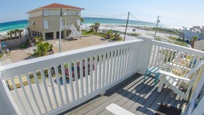 Ein Balkon mit Blick auf den Strand, ein Gebäude und ein Poolbereich.
