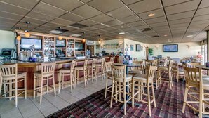 A restaurant with a bar area, multiple seating options, and a patterned floor. - Beautiful oceanfront condo - Bay Watch Unit 338 (North Myrtle Beach)