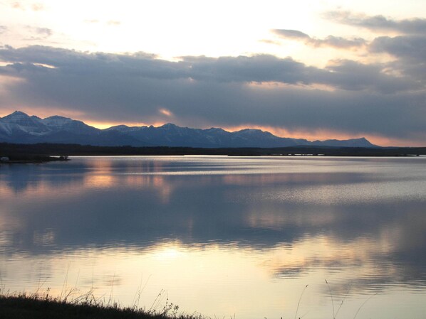 Un lago tranquilo con montañas al fondo y cielo despejado.