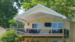 A two-story building with a balcony on the upper floor, surrounded by small trees and a stone wall. - 3BR/2BA Lakefront Property, Includes Boat Slip (Osage Beach)