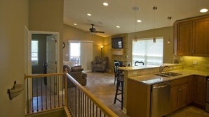 A spacious kitchen with a bar area, a dining area with a sofa, and a staircase leading to an upper level. - 3BR/2BA Lakefront Property, Includes Boat Slip (Osage Beach)