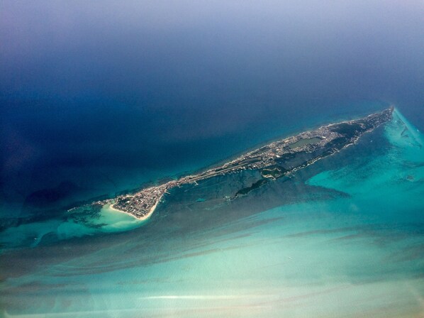 Vista aérea de una zona costera con una extensa franja de tierra, una playa pequeña y aguas azul cristalino.
