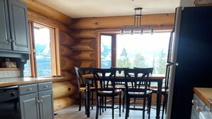 Una cucina con pareti in legno, un tavolo da pranzo con sedie e un frigorifero.