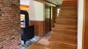 Una scala in legno conduce al secondo piano, una parete in mattoni con un termosifone nero e una porta in legno con vetri.