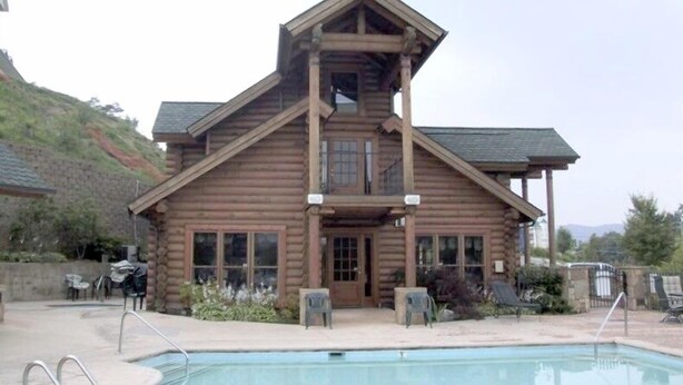 Eine Holzhütte mit Pool und Sitzgelegenheit im Freien.
