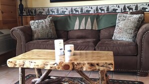Ein rustikaler Holztisch mit einem Bärenbild über einer braunen Ledersofa.