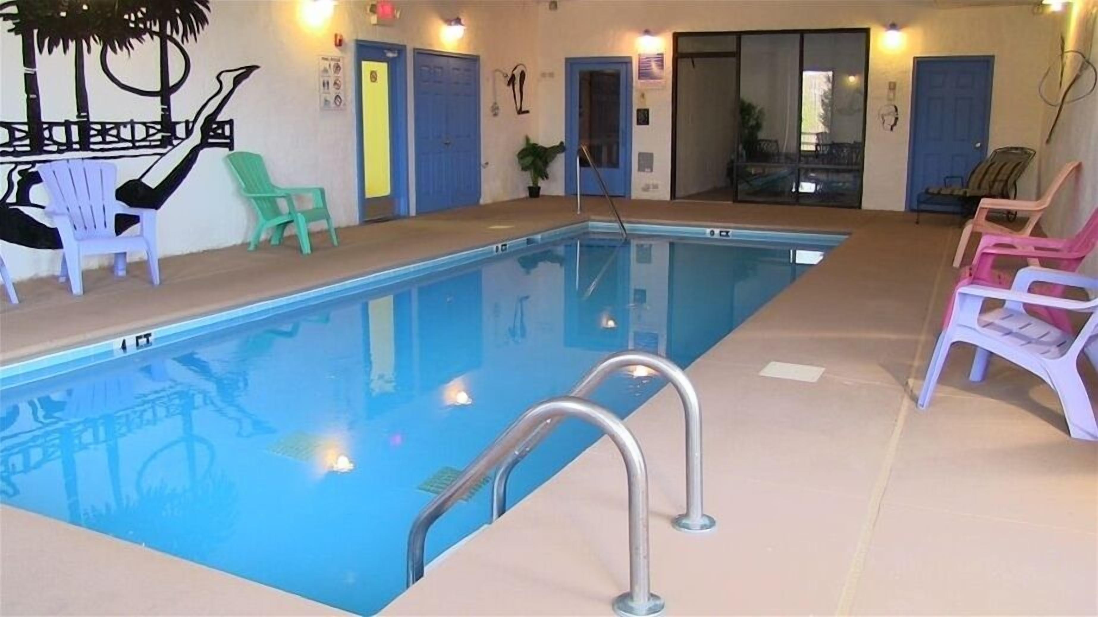 Une piscine intérieure à l’eau claire, entourée de chaises et de portes.