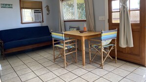 A room with a blue sofa, a wooden table with chairs, a ceiling fan, and a window with curtains. - HALE NIHI, Paia, Maui (Paia)