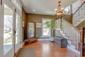 Stunning interior with a grand staircase and hardwood flooring, featuring a large mirror and a potted plant.