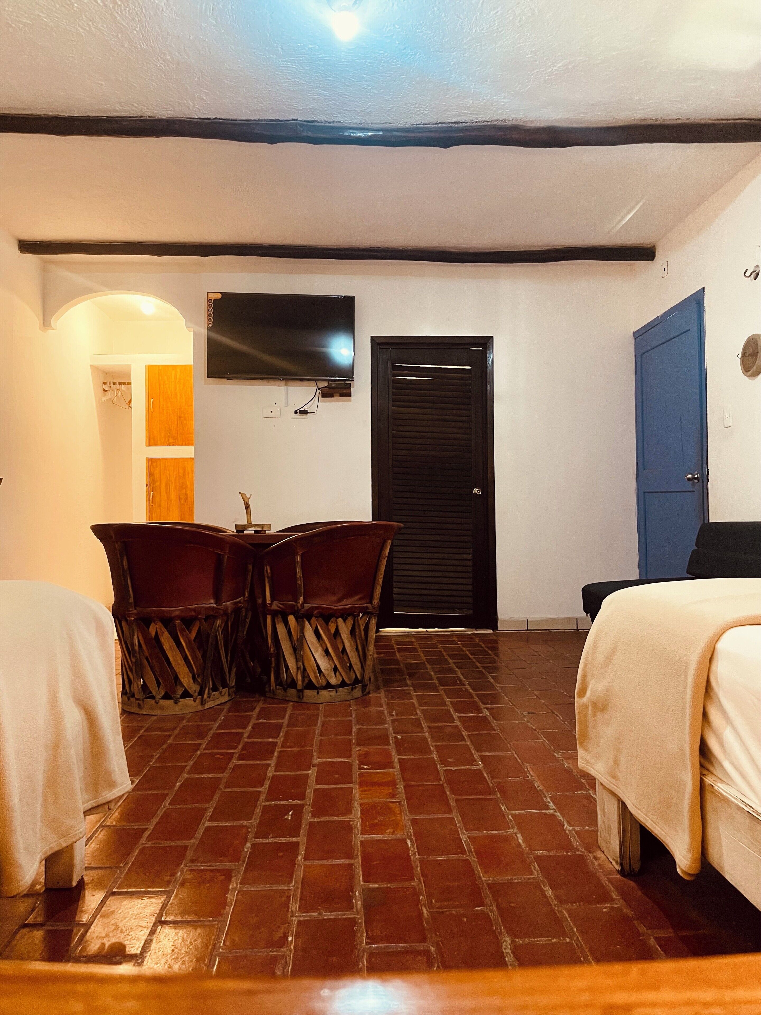 Una habitación con suelo de baldosas, un televisor montado en la pared, una puerta y una cama.