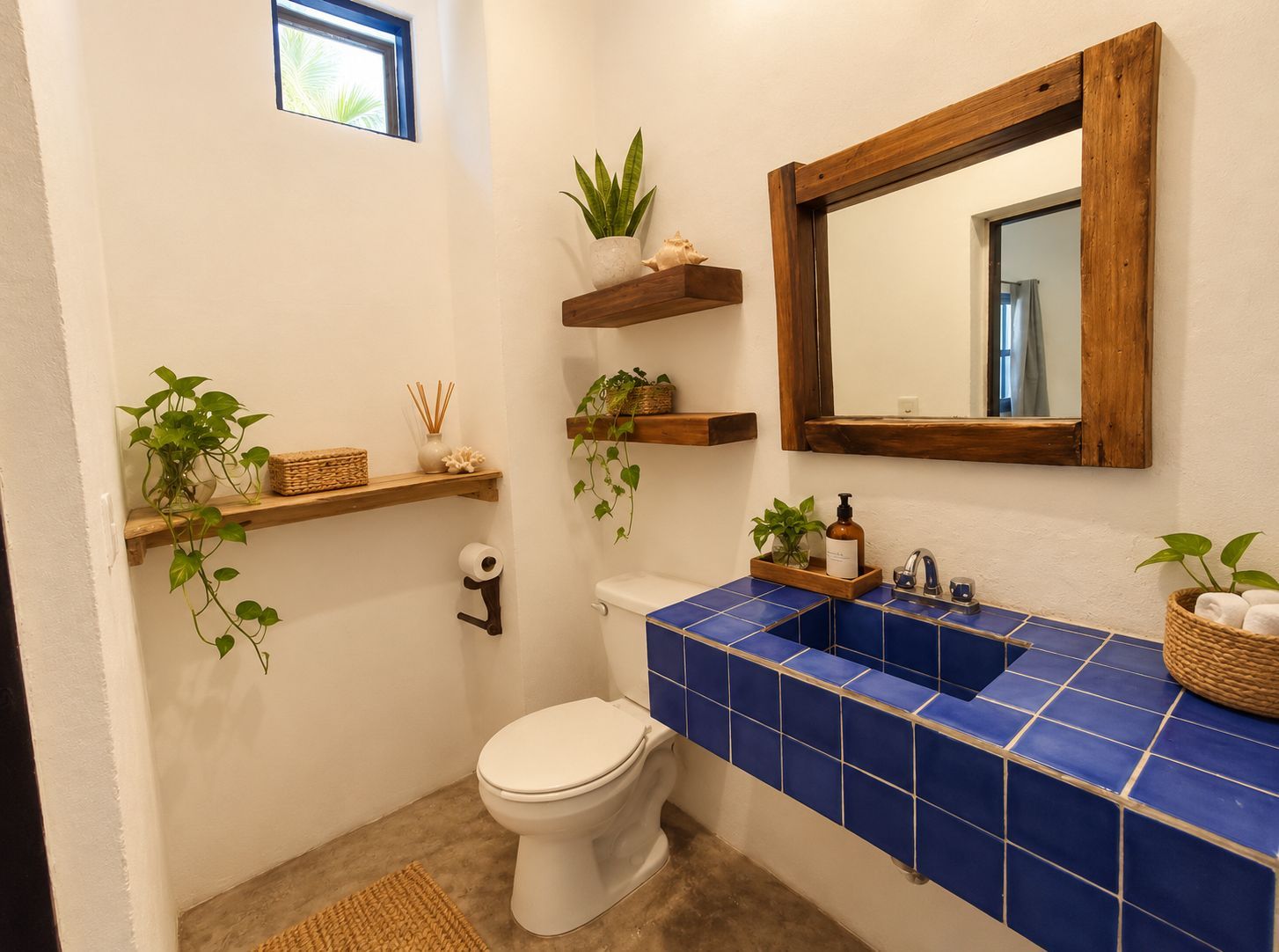 A bathroom with a toilet, blue tiled sink, wooden shelves with plants, a mirror, and a small window.