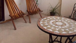 A small patio with two wooden chairs, a round table with a mosaic top, a hanging heart-shaped decoration, and a potted plant. - MIO Tulum Hotel Boutique (Tulum)