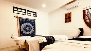 A room with a bed, a massage table, and a large tapestry on the wall. - MIO Tulum Hotel Boutique (Tulum)