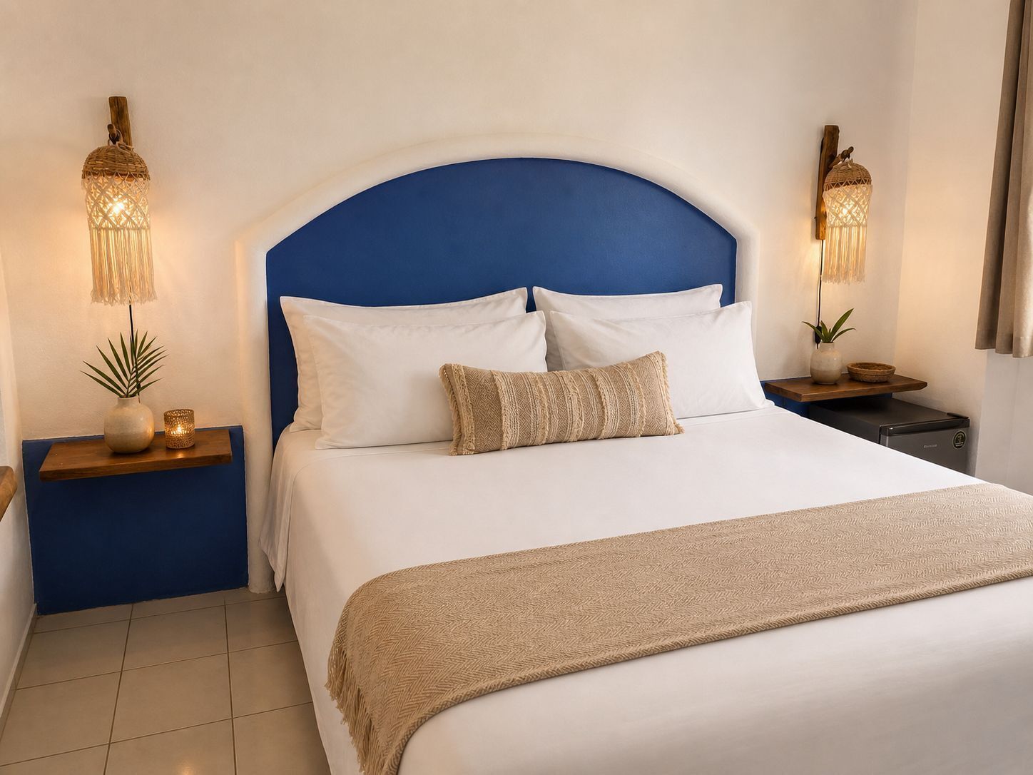 A hotel room with a bed, two bedside tables, a nightstand, a lamp, and a plant.