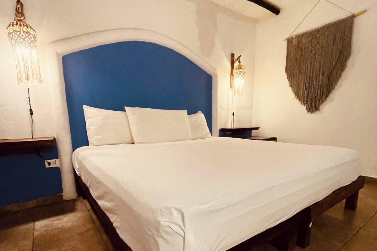 A bedroom with a large bed, two bedside tables, and a blue accent wall.