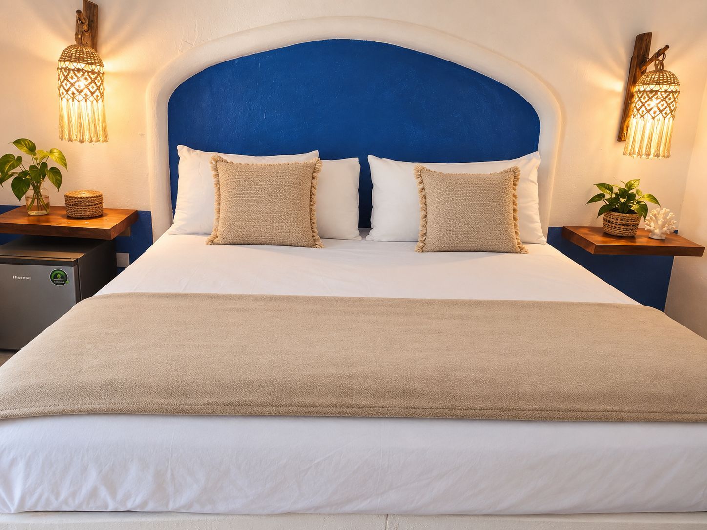 Una habitación de hotel con una cama grande, dos mesitas de noche y lámparas de pared.