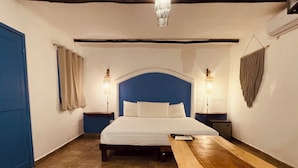 A bedroom with a bed, bedside tables, a bench, a colorful trash bin, and a chandelier. - MIO Tulum Hotel Boutique (Tulum)