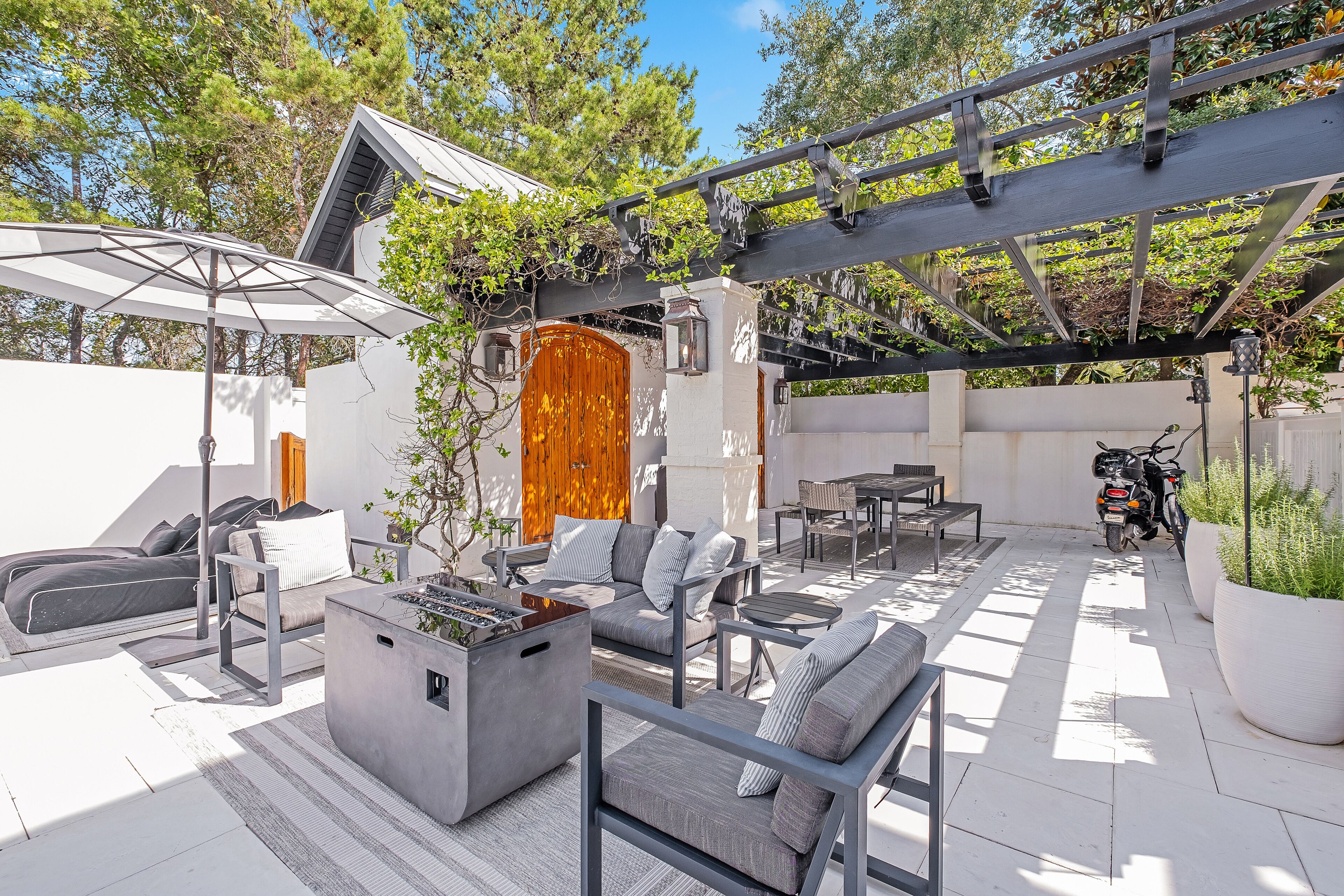 An outdoor patio with modern furniture, a fire pit, and a pergola.