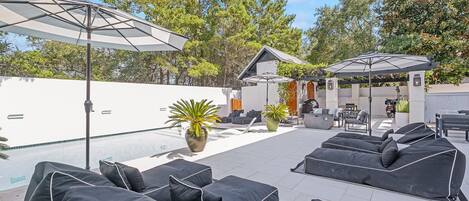 Un patio con mobiliario exterior, sombrillas y plantas en macetas.