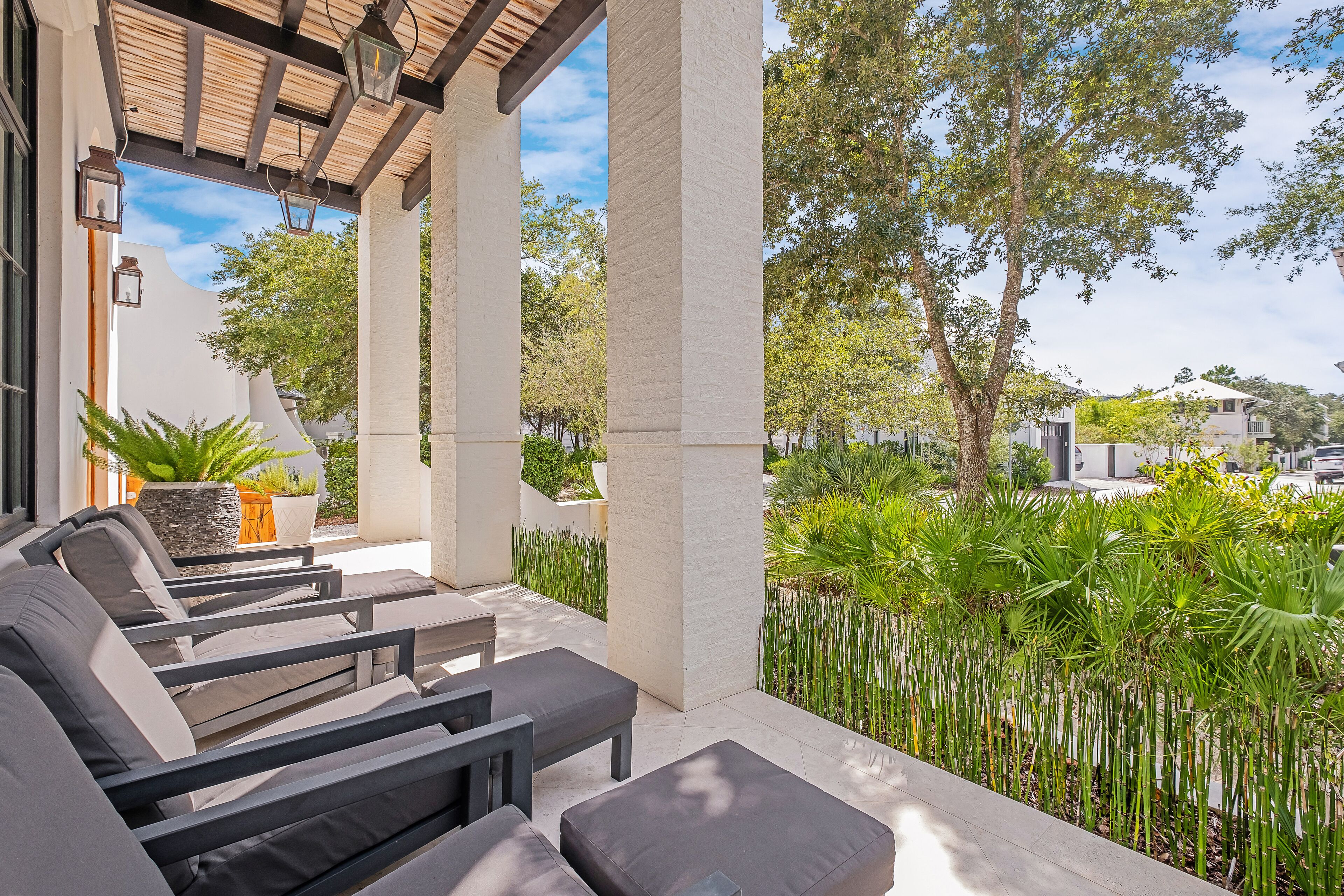 A covered outdoor seating area with modern furniture and a view of the surrounding greenery and buildings.