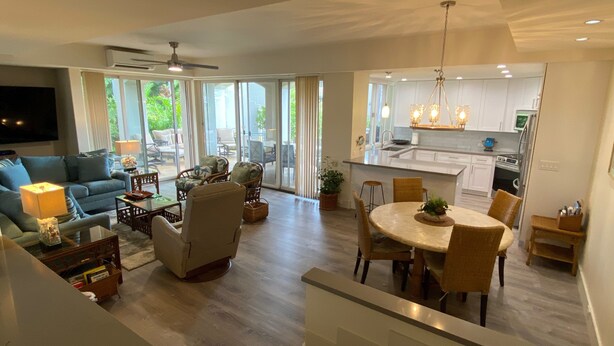 A spacious living area with a sofa, chairs, a dining table, and a kitchen in the background.