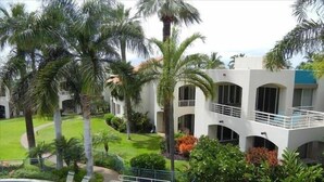 A hotel with a pool, palm trees, and a well-maintained lawn.