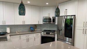 A modern kitchen with white cabinets, stainless steel appliances, and a marble countertop.